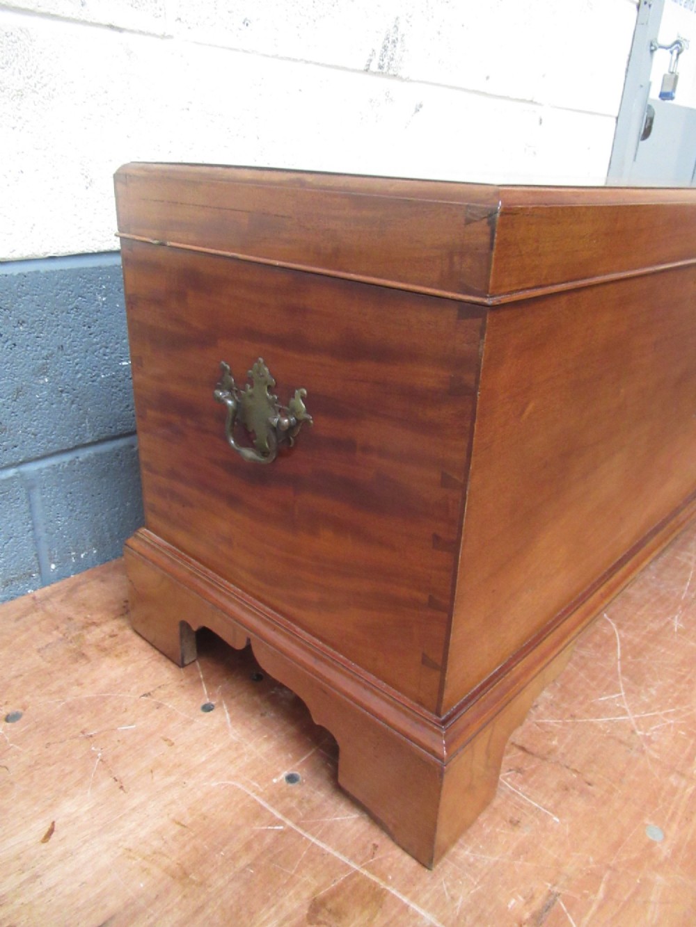 An open mahogany fitted storage chest with internal vertical wood dividers, a keyhole with a dark escutcheon, and a hinged lid. View III