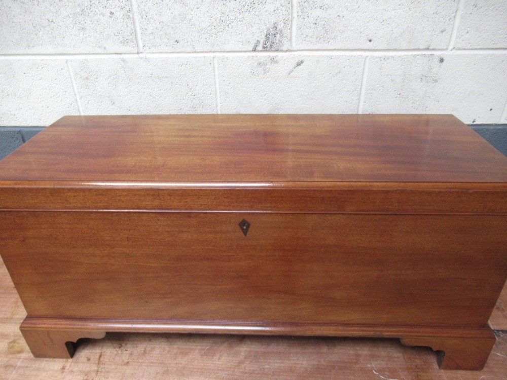 An open mahogany fitted storage chest with internal vertical wood dividers, a keyhole with a dark escutcheon, and a hinged lid. View V