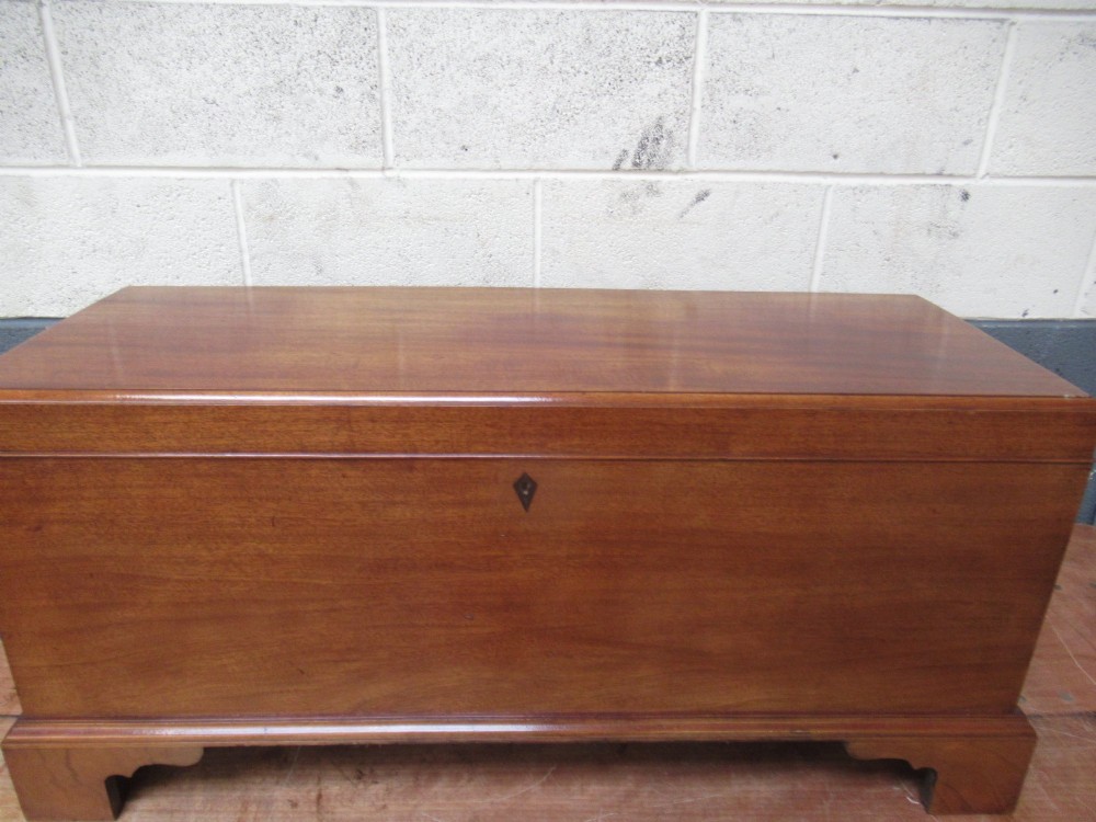 An open mahogany fitted storage chest with internal vertical wood dividers, a keyhole with a dark escutcheon, and a hinged lid. View X