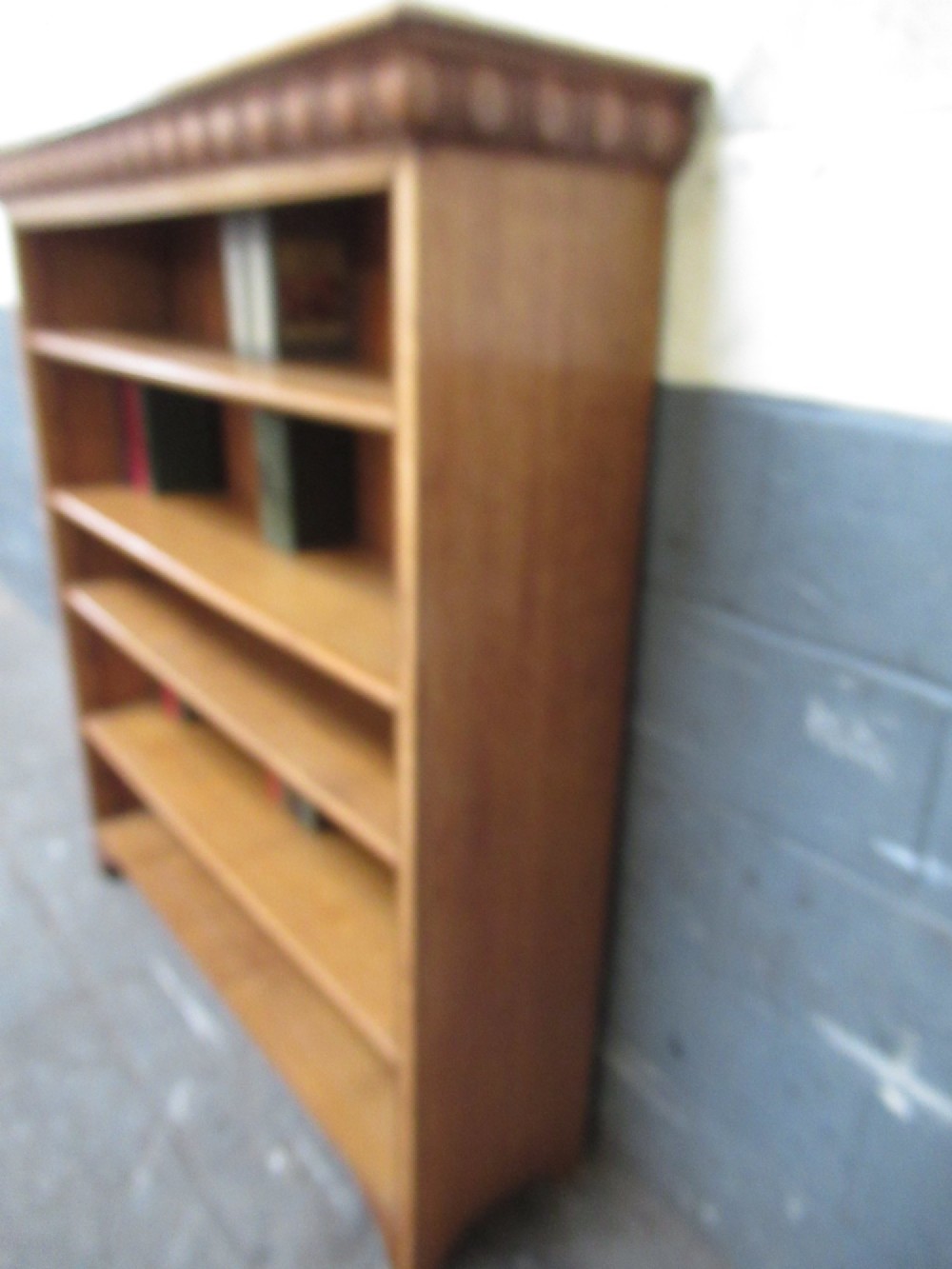 A late Victorian light oak open bookcase featuring five shelves, a planked pine back, and a carved egg-and-dart cornice moulding. View II