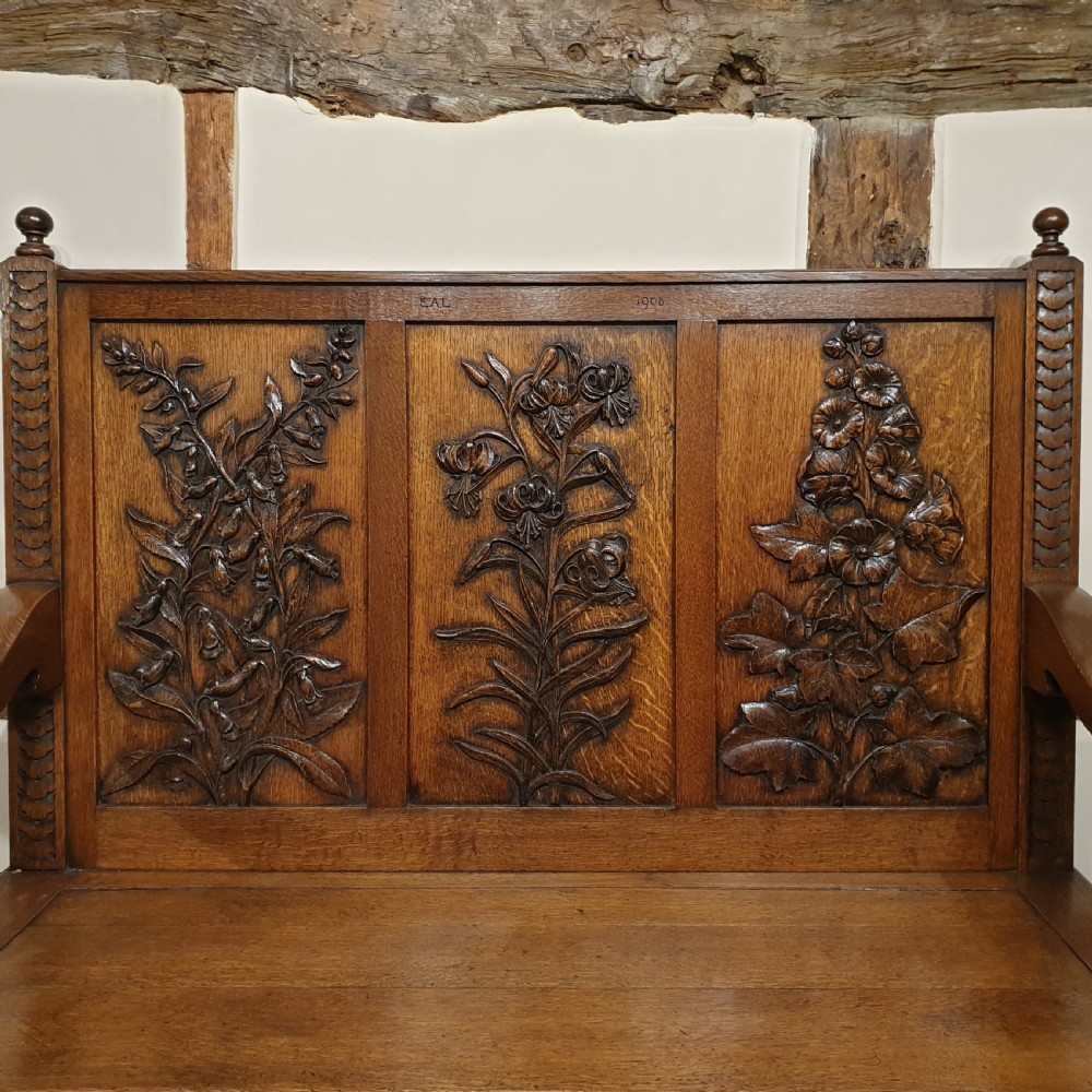 Carved oak box settle - uniquely decorated with garden flowers - initialled & dated 1908 View II