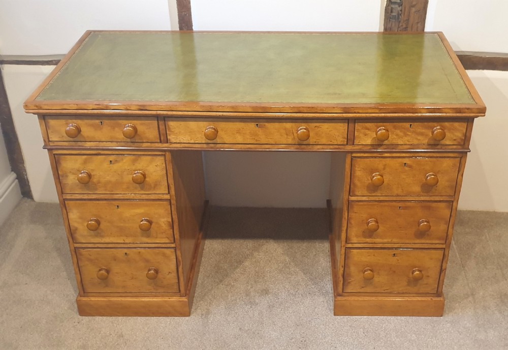 A 19th-century satin birch pedestal desk featuring nine drawers with turned wooden handles and a green leather inset writing surface. View IX