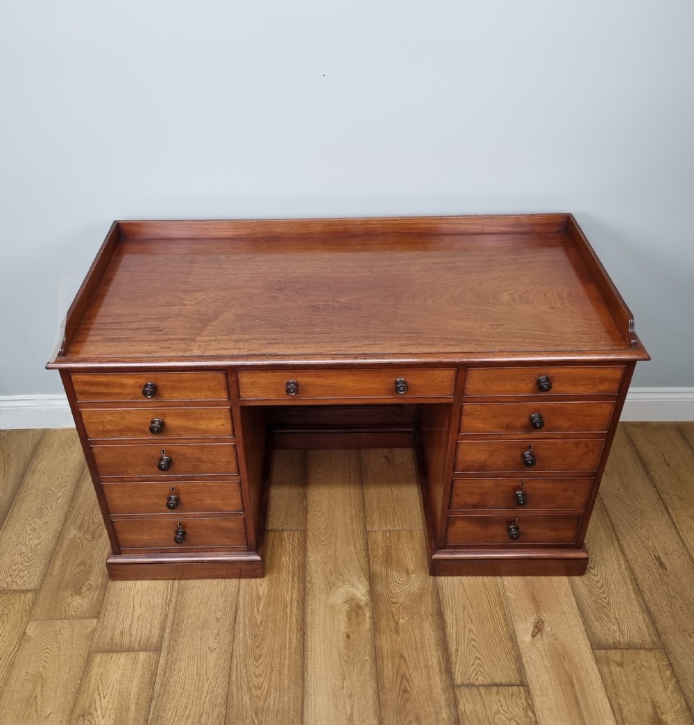 An early nineteenth-century mahogany pedestal desk featuring a raised tray top, nine drawers with turned wooden handles, and a central kneehole. View II