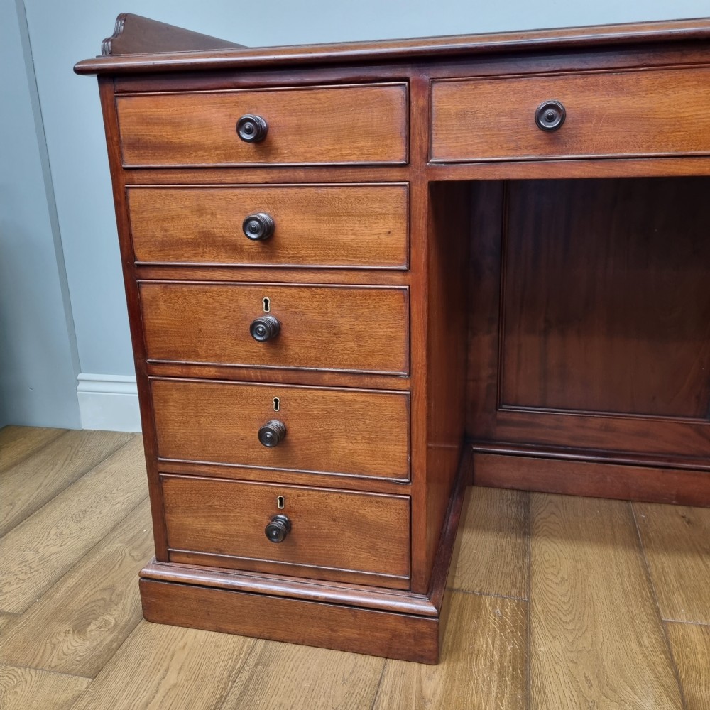 An early nineteenth-century mahogany pedestal desk featuring a raised tray top, nine drawers with turned wooden handles, and a central kneehole. View III