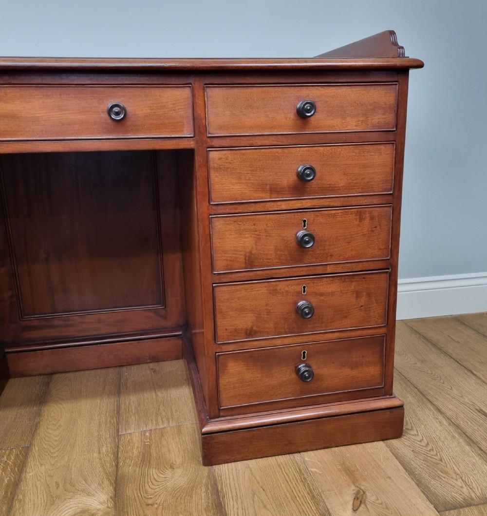 An early nineteenth-century mahogany pedestal desk featuring a raised tray top, nine drawers with turned wooden handles, and a central kneehole. View IV