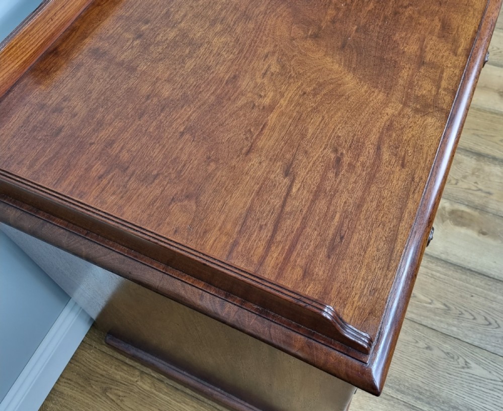 An early nineteenth-century mahogany pedestal desk featuring a raised tray top, nine drawers with turned wooden handles, and a central kneehole. View V