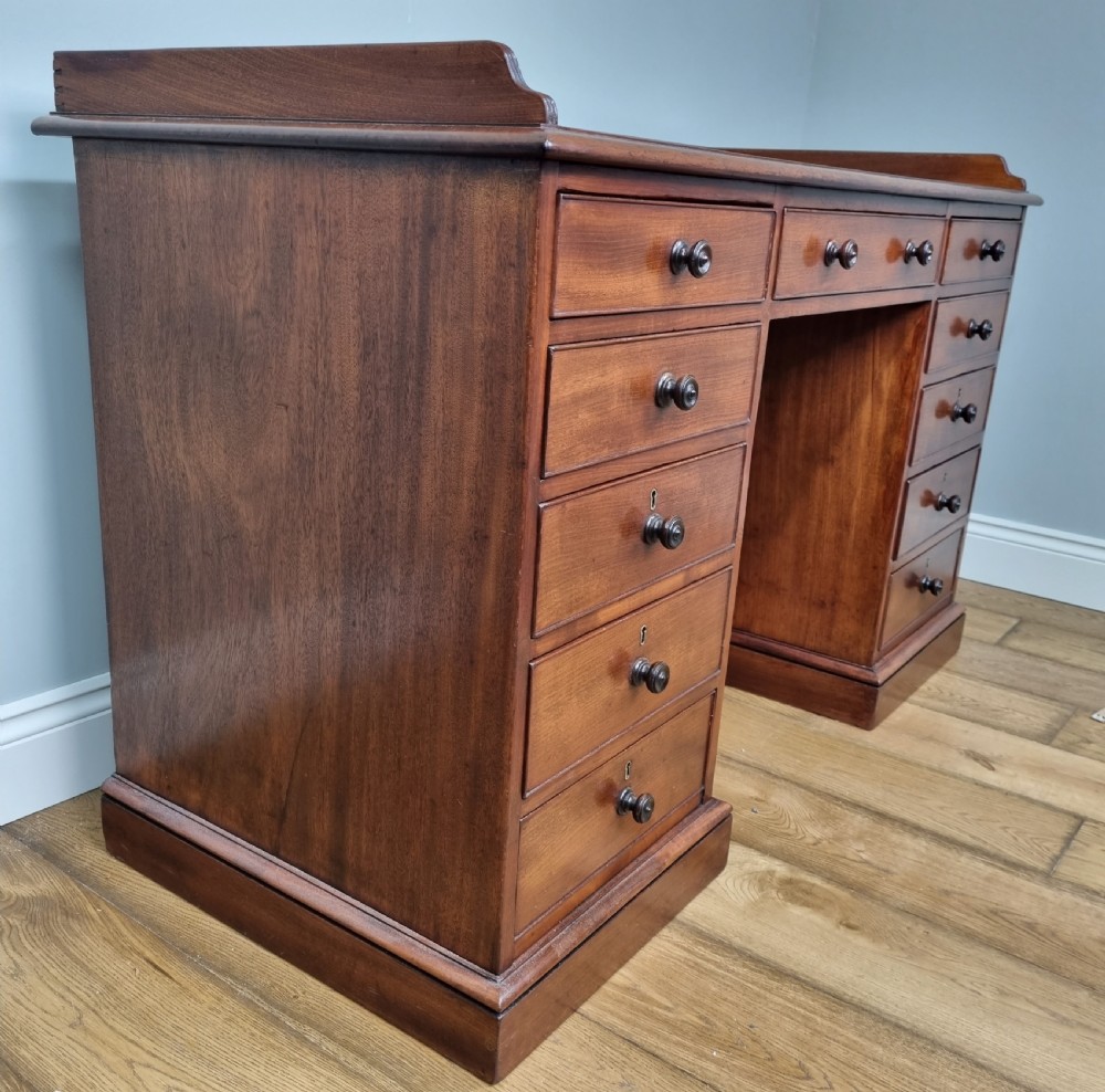 An early nineteenth-century mahogany pedestal desk featuring a raised tray top, nine drawers with turned wooden handles, and a central kneehole. View VI
