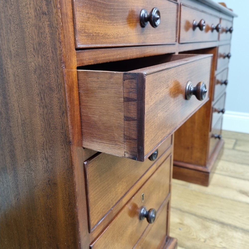 An early nineteenth-century mahogany pedestal desk featuring a raised tray top, nine drawers with turned wooden handles, and a central kneehole. View VII