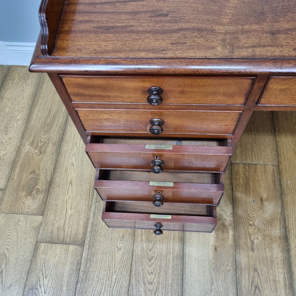 An early nineteenth-century mahogany pedestal desk featuring a raised tray top, nine drawers with turned wooden handles, and a central kneehole. View VIII
