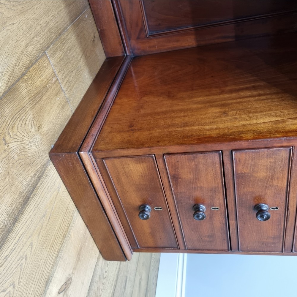 An early nineteenth-century mahogany pedestal desk featuring a raised tray top, nine drawers with turned wooden handles, and a central kneehole. View X