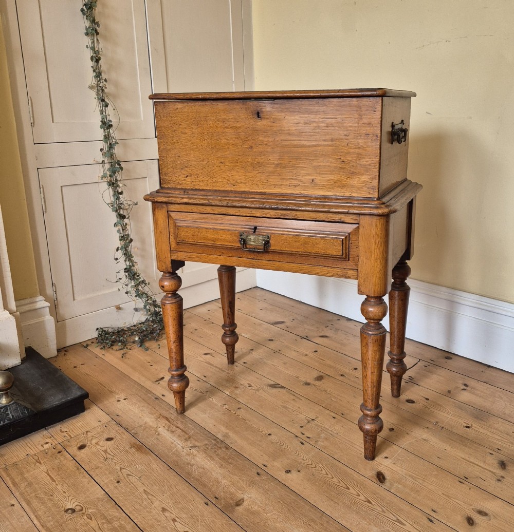 A late 19th-century golden oak ticket collecting box with internal compartments set atop a matching turned-leg stand. View II