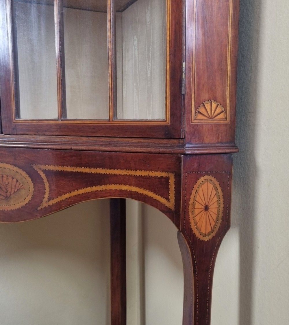 A mahogany Georgian corner display cabinet on stand featuring gothic astragal glazed doors, a swan-neck pediment, marquetry inlays, and curved lower legs. View VII