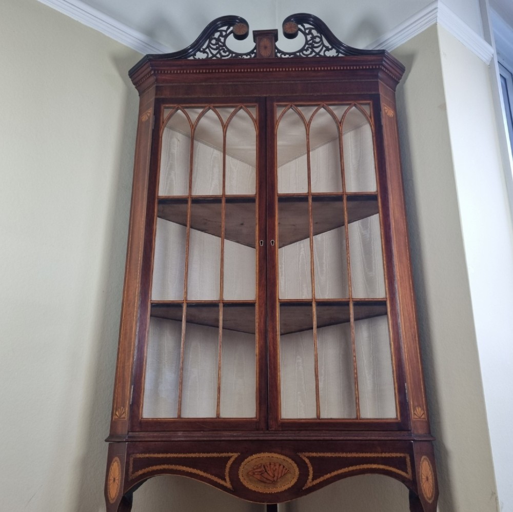 A mahogany Georgian corner display cabinet on stand featuring gothic astragal glazed doors, a swan-neck pediment, marquetry inlays, and curved lower legs. View IX