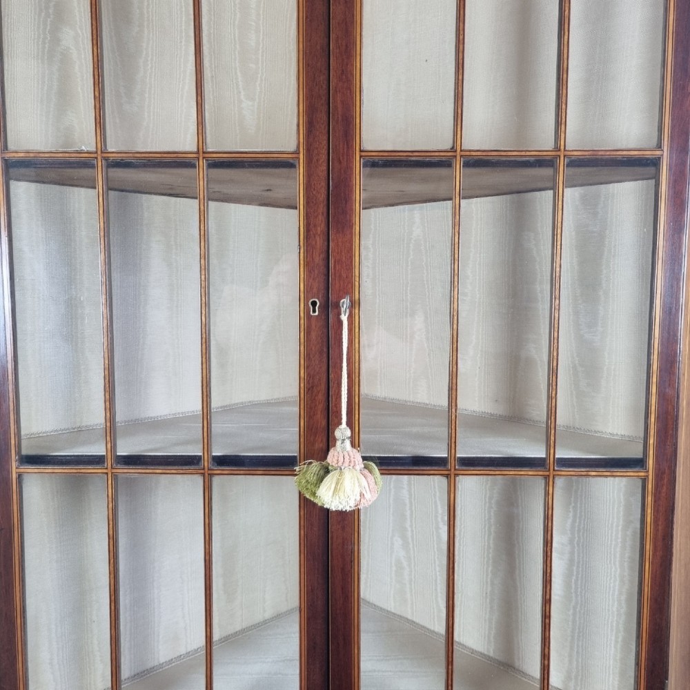 A mahogany Georgian corner display cabinet on stand featuring gothic astragal glazed doors, a swan-neck pediment, marquetry inlays, and curved lower legs. View X