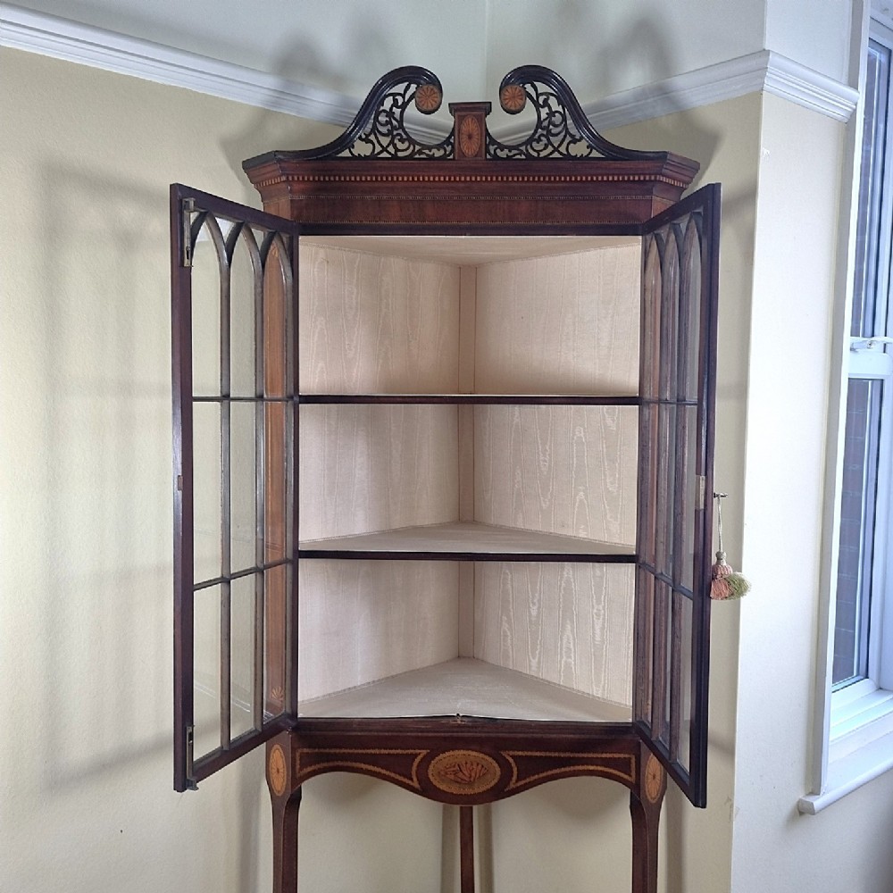 A mahogany Georgian corner display cabinet on stand featuring gothic astragal glazed doors, a swan-neck pediment, marquetry inlays, and curved lower legs. View XII