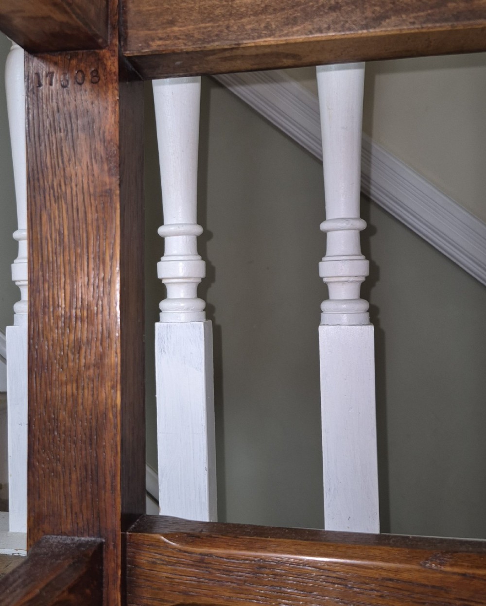 A long Victorian Gothic Revival solid oak bench featuring turned legs, a rectangular lower stretcher frame, and a dark green velvet upholstered cushion top. View IX