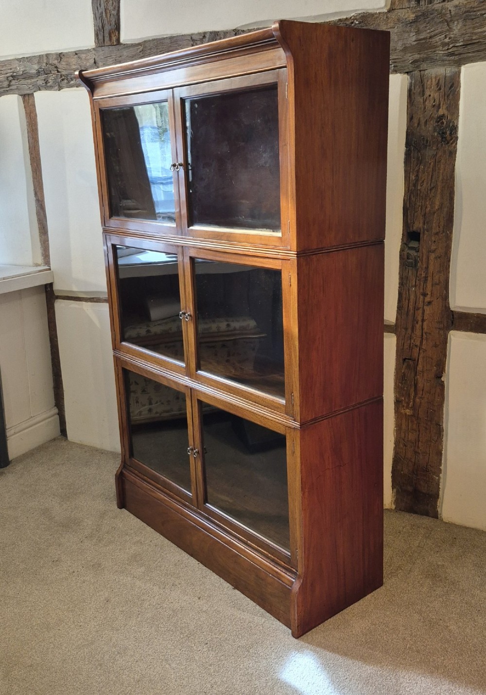 A three-tier warm brown oak sectional bookcase with double glazed doors and brass ring handles. View IV