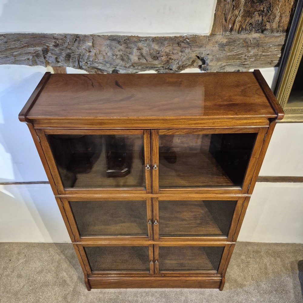 A three-tier warm brown oak sectional bookcase with double glazed doors and brass ring handles. View V