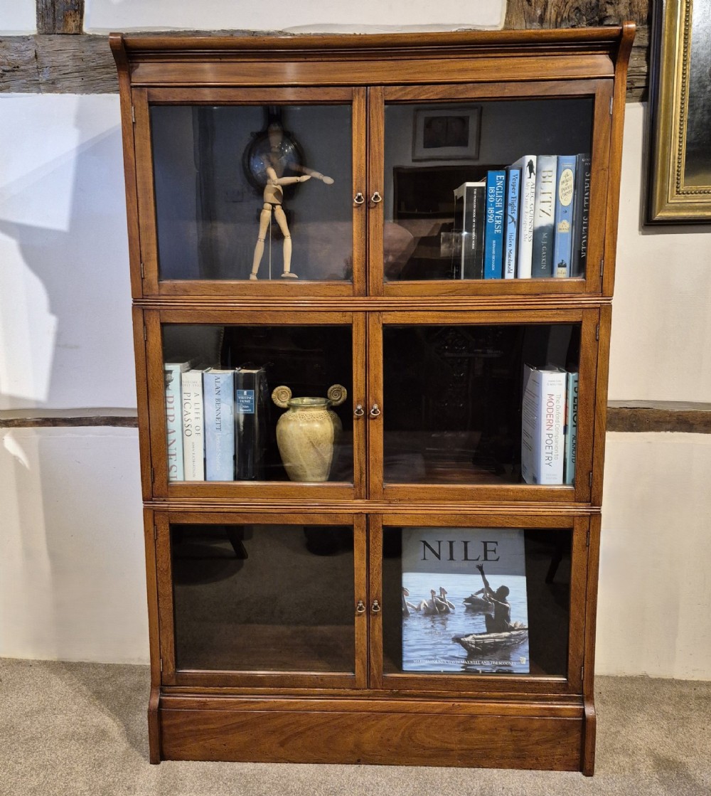 A three-tier warm brown oak sectional bookcase with double glazed doors and brass ring handles. View XII