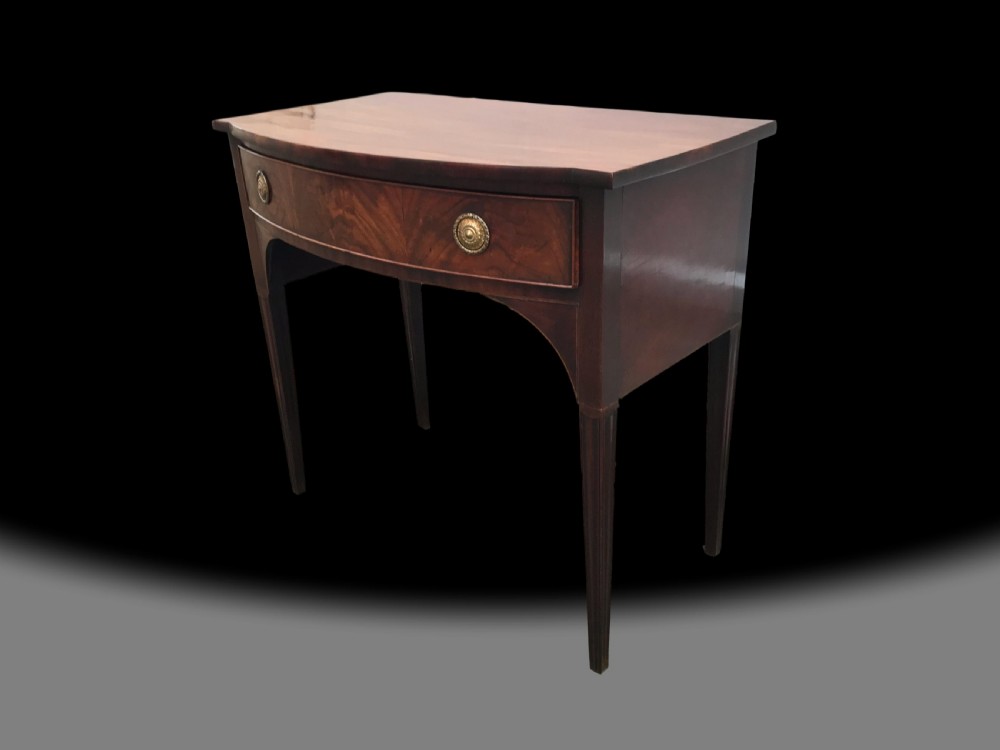 A late 18th-century George III mahogany bow front side table featuring a central drawer with circular brass handles and slender tapered legs. View III