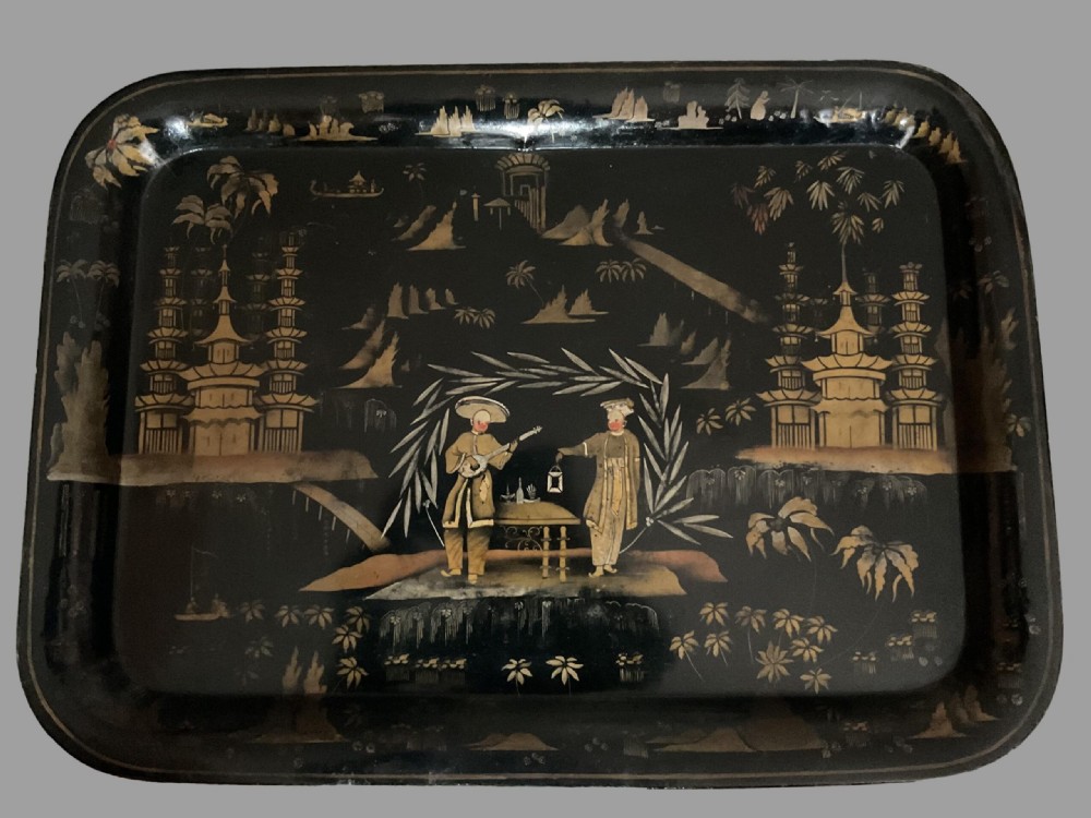 A rectangular black lacquered metal tray decorated with hand-painted gold chinoiserie scenes featuring pagodas, figures, and foliage.
