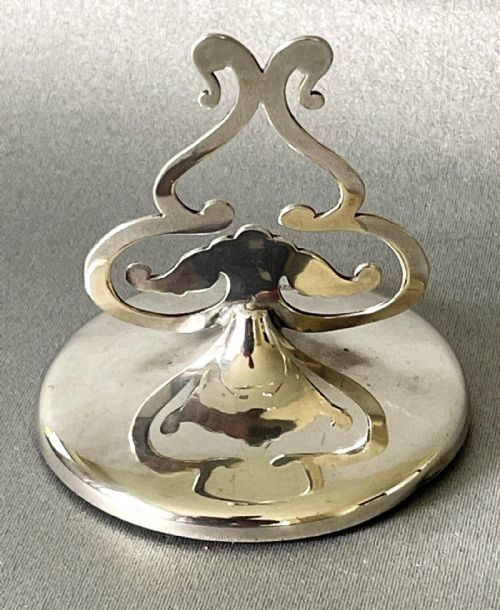 fig 1. An Edwardian sterling silver menu card holder with an openwork scrollwork clip set upon a circular hallmarked base.