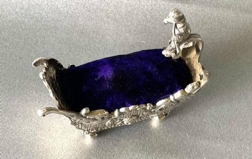 fig 1. A Victorian silver novelty pin cushion shaped like an ornate sledge with a purple velvet cushion interior.