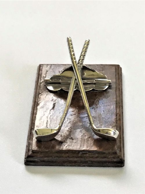 fig 1. An Edwardian silver desk clip crafted in the shape of crossed golf clubs, mounted on a rectangular dark oak wood base.