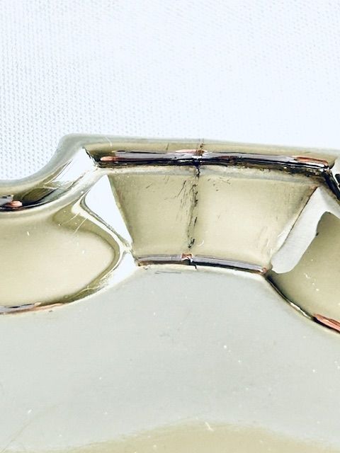 fig 1. A circular 18th-century silver card tray featuring a scalloped piecrust rim, an engraved heraldic crest in the centre, and short cast feet.