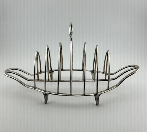 fig 1. A silver six-slice toast rack featuring arched wire divisions, an oval loop carry handle, and four small supportive feet.