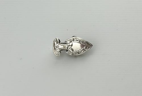 fig 1. An Edwardian sterling silver napkin clip featuring a shield shape with hand-engraved foliate decoration.