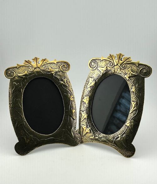 fig 1. A pair of decorative brass picture frames featuring embossed ivy leaf motifs around oval openings against a stippled background.
