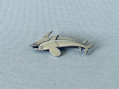 fig 1. A sterling silver brooch depicting two stylised dolphins swimming together in profile.