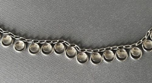 fig 1. A vintage silver necklace featuring a chain edged with a row of small, uniform circular concave disc elements.