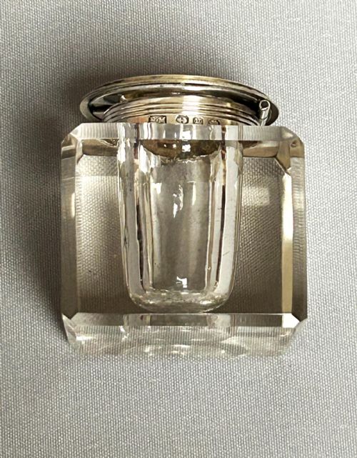 fig 1. A heavy square glass inkwell with a hallmarked silver collar and a pale yellow guilloche enamel lid featuring a hand-painted pink rose motif.