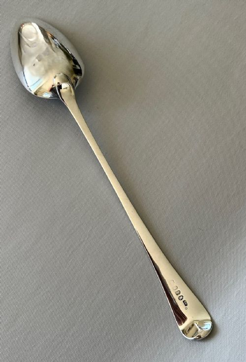 fig 1. An 18th-century sterling silver basting spoon with a deep oval bowl and a long tapered handle.