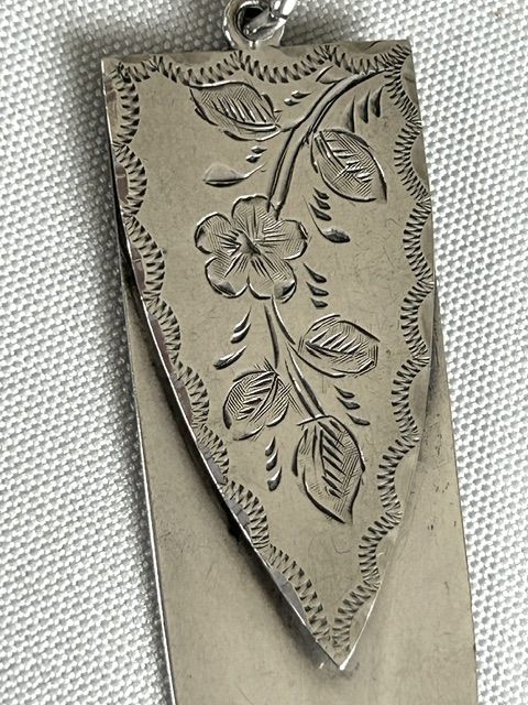 fig 1. An Edwardian silver clip bookmark featuring a pointed blade shape and engraved floral detailing on the upper clip section.