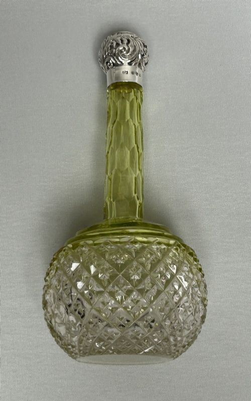 fig 1. A Victorian yellow cut glass cologne bottle featuring a faceted neck, diamond-patterned base, and an embossed sterling silver cap.
