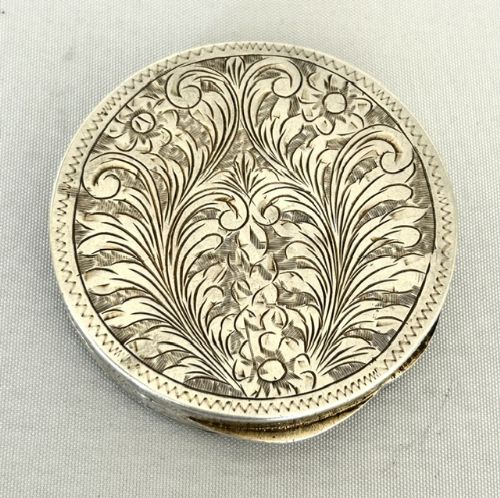 fig 1. A circular silver vanity compact featuring a hand-painted enamel pastoral scene framed by a turquoise border.