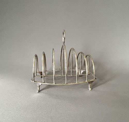 fig 1. A Georgian sterling silver toast rack featuring seven wire arches, a central ring handle, and four small feet.
