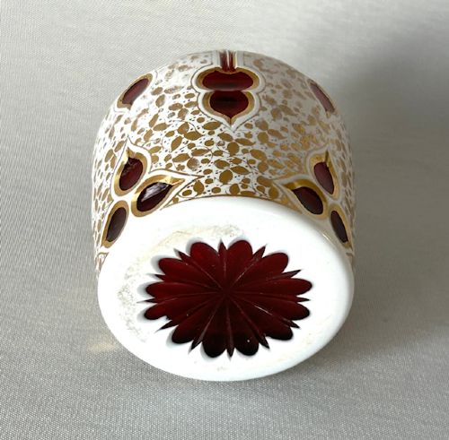 fig 2. An Edwardian Bohemian glass scent bottle featuring ruby red cut-outs over a white gilded pattern, topped with a hallmarked silver cap.