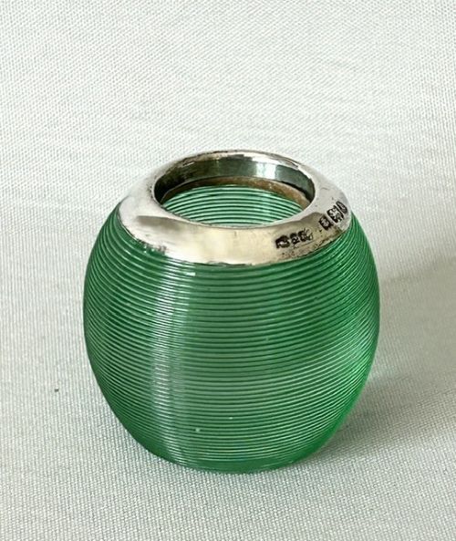 fig 1. A spherical emerald green glass match striker featuring ribbed horizontal grooves and a hallmarked sterling silver collar at the rim.
