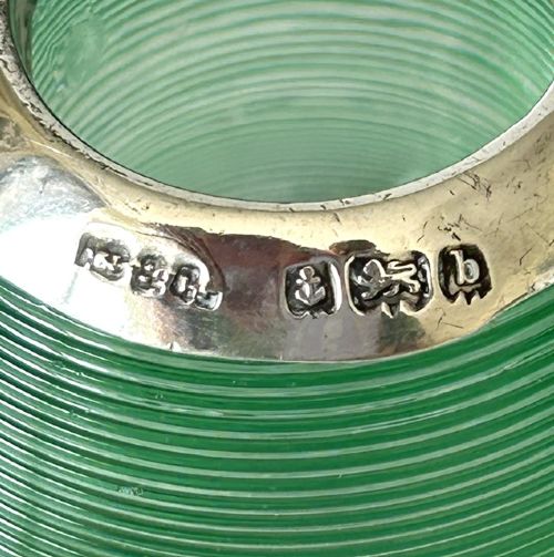 A spherical emerald green glass match striker featuring ribbed horizontal grooves and a hallmarked sterling silver collar at the rim. View VI