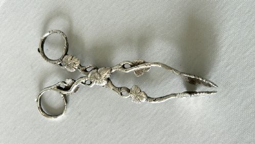 A pair of Victorian cast silver tea tongs designed with naturalistic vine branch handles, leaf motifs, and leaf-shaped grips. View V