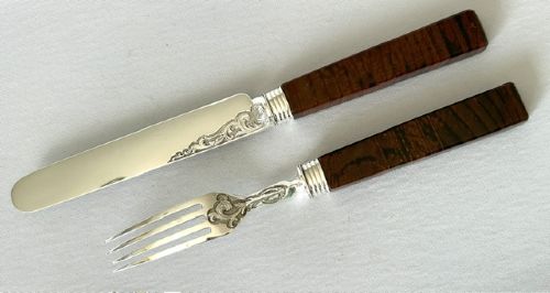 A Victorian silver dessert knife and fork featuring engraved scrollwork on the blade and tines with polished rectangular dark brown agate handles. View IV