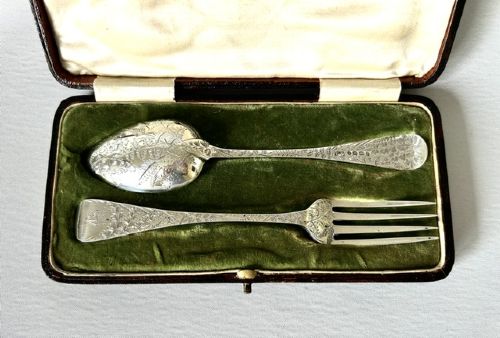 fig 1. A late Victorian silver spoon and fork with engraved pattern detailing, displayed inside an open dark green velvet-lined presentation box with a cream silk interior.