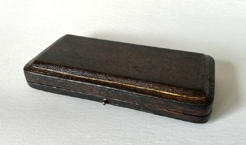 A late Victorian silver spoon and fork with engraved pattern detailing, displayed inside an open dark green velvet-lined presentation box with a cream silk interior. View III