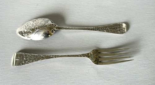 A late Victorian silver spoon and fork with engraved pattern detailing, displayed inside an open dark green velvet-lined presentation box with a cream silk interior. View IV
