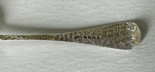 A late Victorian silver spoon and fork with engraved pattern detailing, displayed inside an open dark green velvet-lined presentation box with a cream silk interior. View VI