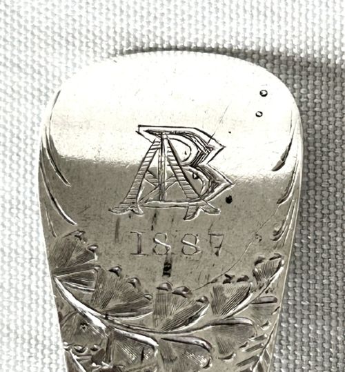 A late Victorian silver spoon and fork with engraved pattern detailing, displayed inside an open dark green velvet-lined presentation box with a cream silk interior. View VII